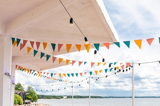 A garland of lamps and cute triangular flags of red yellow and turquoise colors for an outdoor party