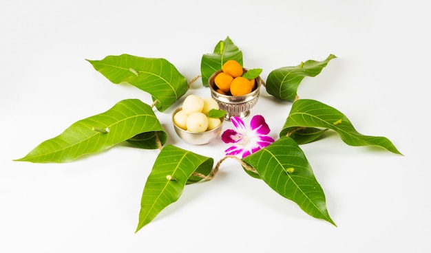 Garland of mango leaves with indian sweet pedha and orchid flower .