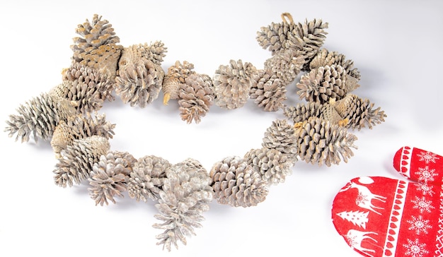 A garland of pine cones covered with imitation snow and a red mitten on a light background