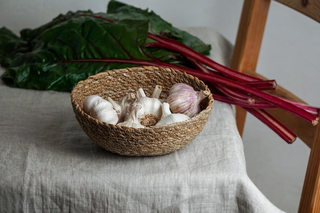 Garlic in a bowl of withy and red chard on a linen tablecloth