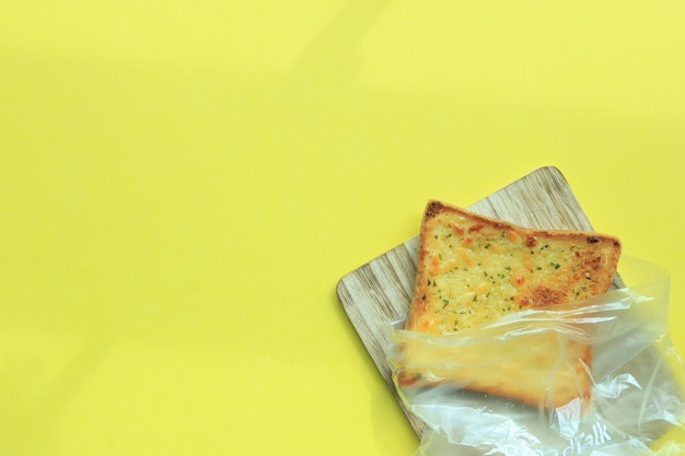 Garlic bread on chopping board on yellow background