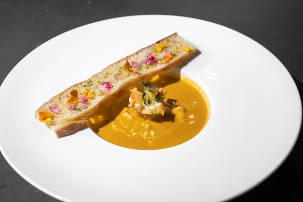 Garlic Bread with Creamy TomYamKung Soup on white dish in studio light decorated with flower petal on it