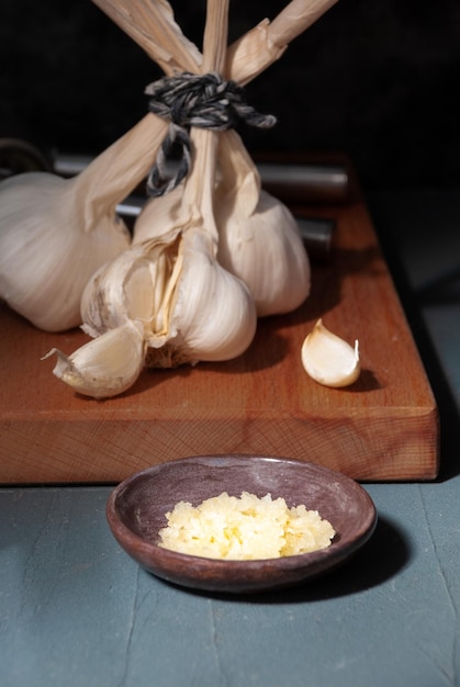 Garlic cloves on a cutting board with a wooden spoon.