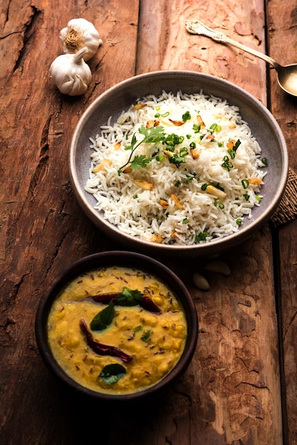 Garlic Fried Rice Or Pulav using Basmati Rice and Lahsun, served with Dal Tadka over moody background, selective focus