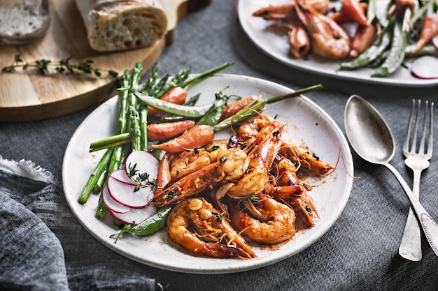 Photo garlic and herby prawn with sauteed asparagus, baby carrot and snap pea