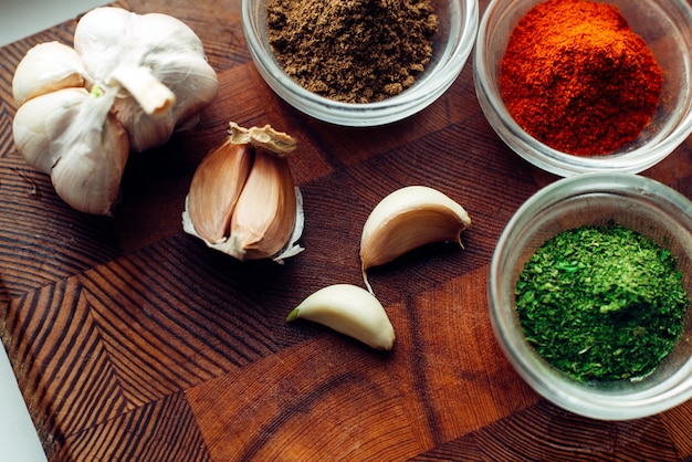 Garlic and jars with spices on wooden wall