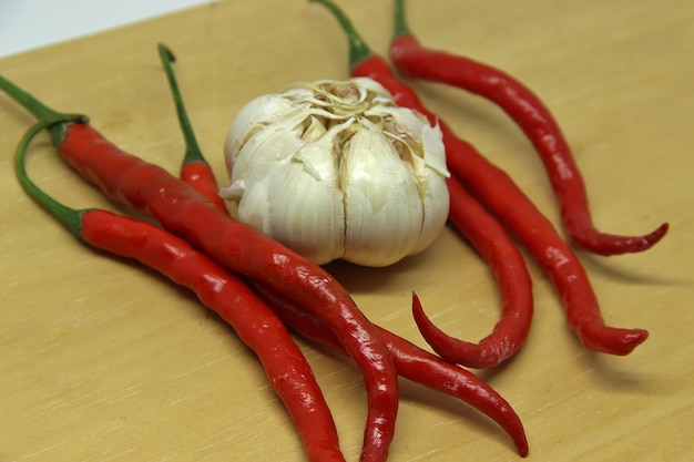 a garlic on a table with a bunch of red chili peppers