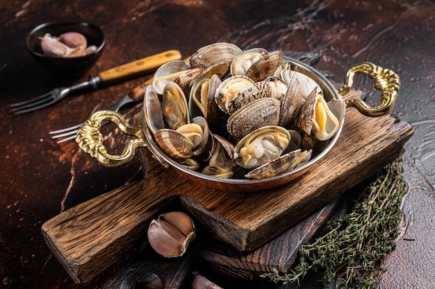 Garlic white wine shells Clams, vongole in a skillet with herbs. Dark background. Top view.