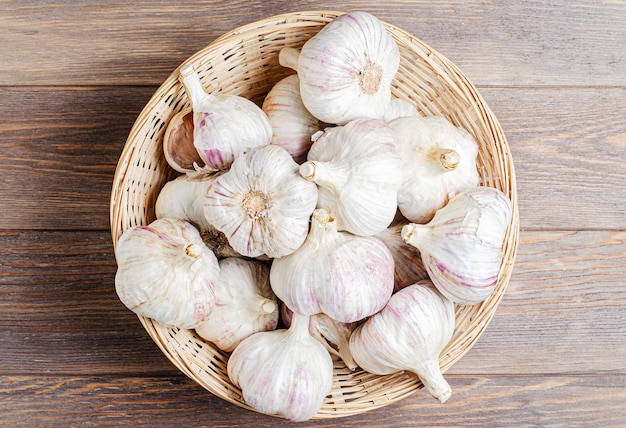 Garlic in a wicker basket Brown wooden background Copy space