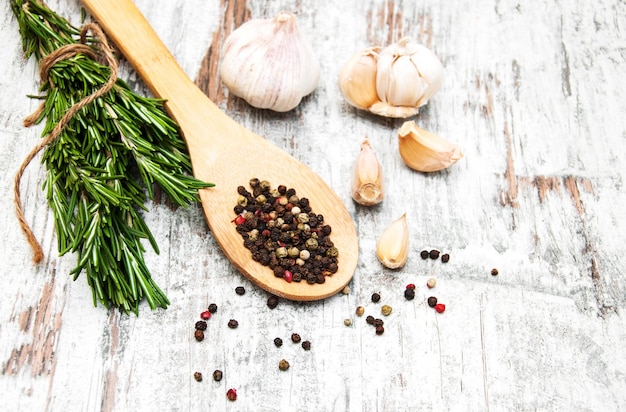 Garlic with rosemary and pepper on a old wooden background