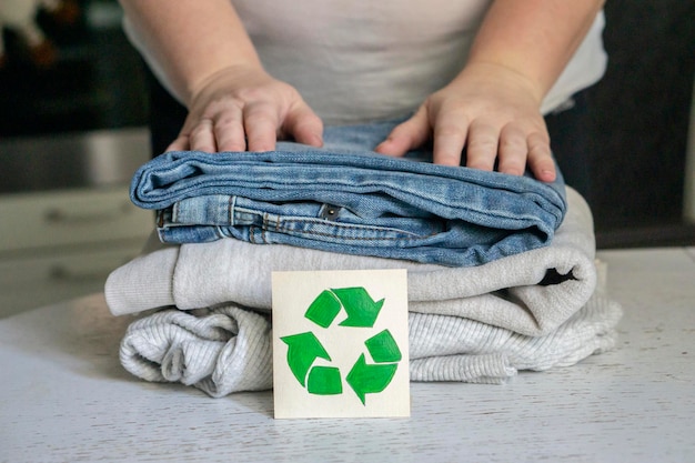 Garment recycling concept. A stack of clothes is on the recycling table. Collection of clothes for recycling