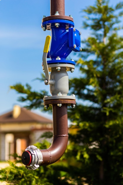 Gas pipe with a manual valve closeup against the blue sky