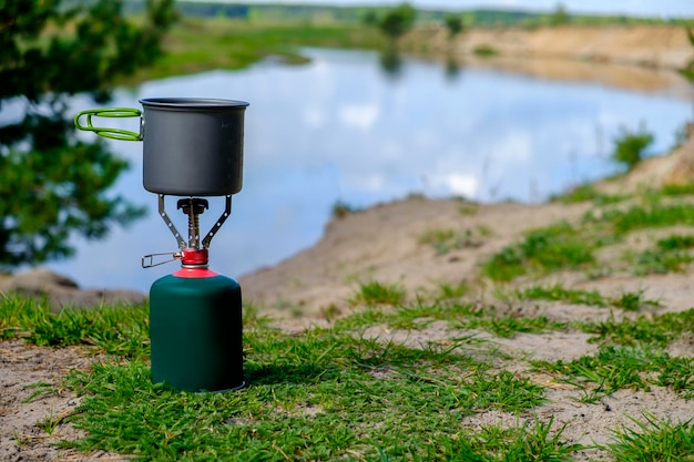 Gas tourist burner with cook pot and background river