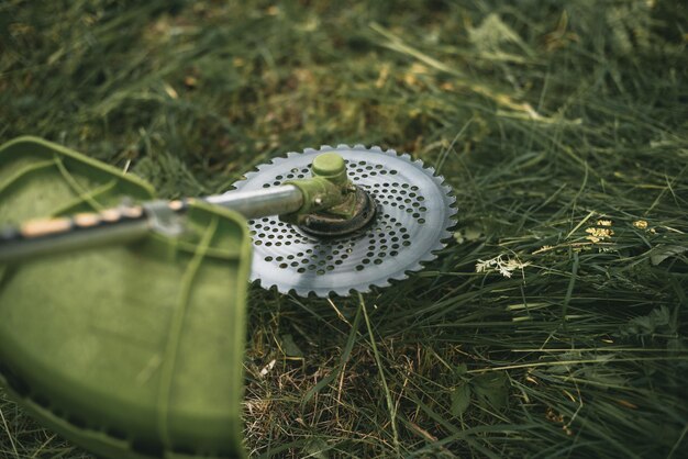 Gasoline trimmer head on green grass. Round trimmer blade.