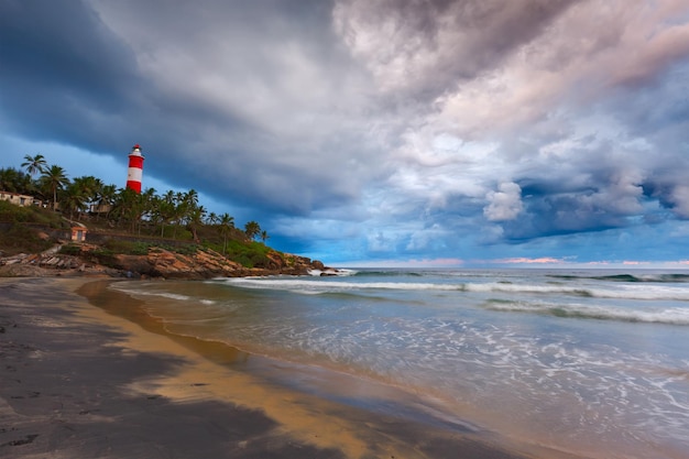 Gathering storm on beach and lighthouse on sunset Kerala India