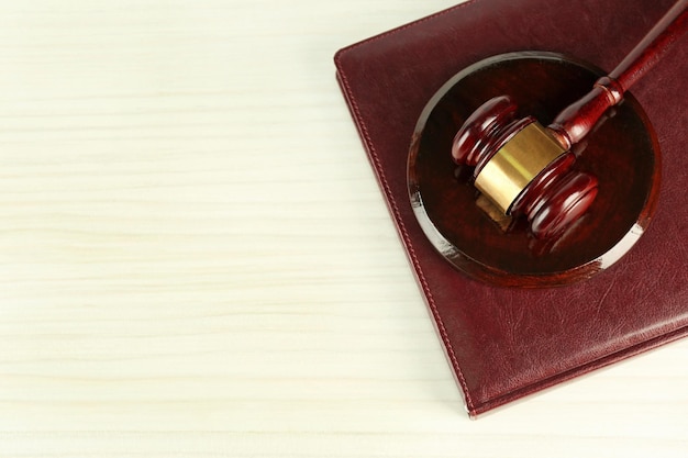 Gavel and book on light wooden background