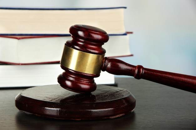 Gavel and books on table on light background