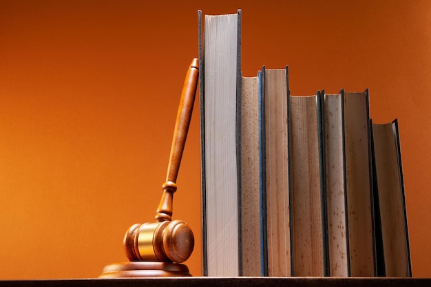 Photo gavel hammer lean on row of books against orange background