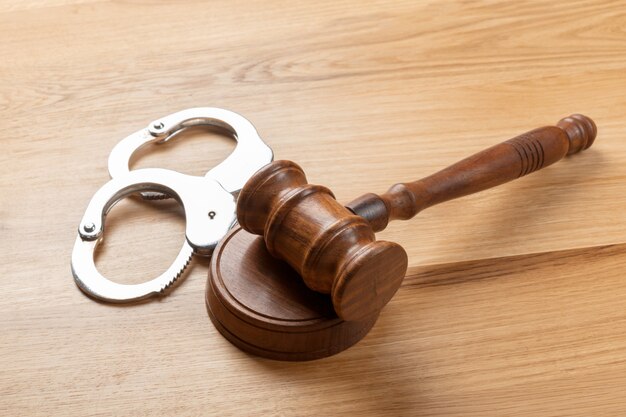 Gavel and handcuffs on wooden table background