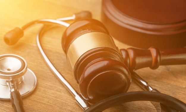 Gavel and stethoscope on wooden background, symbol photo for bungling and medical error