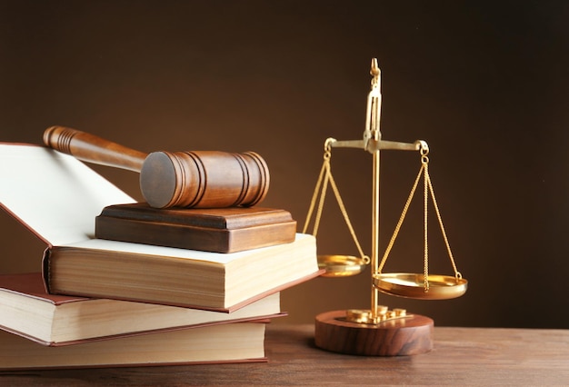 Gavel with books and scales on brown background