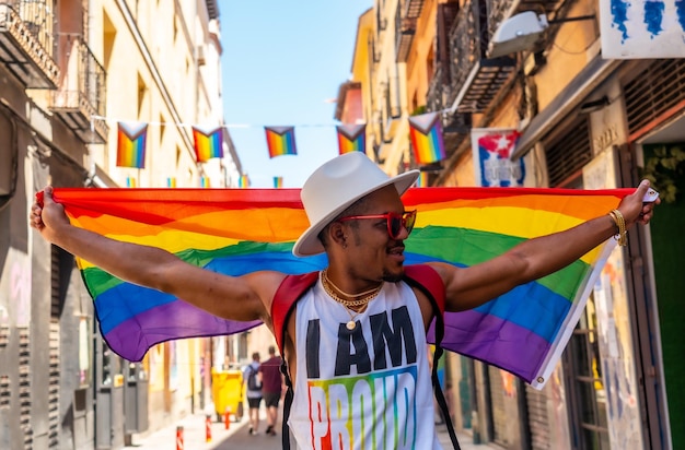 A gay black man walking at the pride party with an LGBT flag