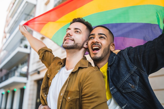 Gay couple embracing and showing their love with rainbow flag