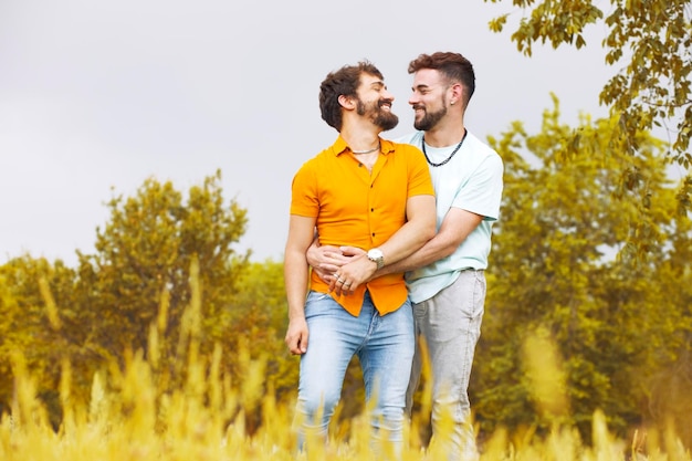 Gay couple in the park Young man hugging his boyfriend