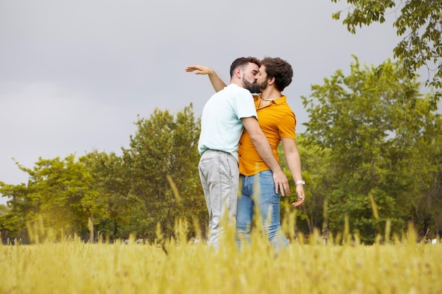 Gay couple in the park Young man hugging and kissing his boyfriend