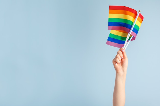 Gay flags in women's hand on grey 