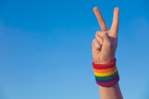 Gay pride concept Hand making a V peace sign with gay pride LGBT rainbow flag wristband