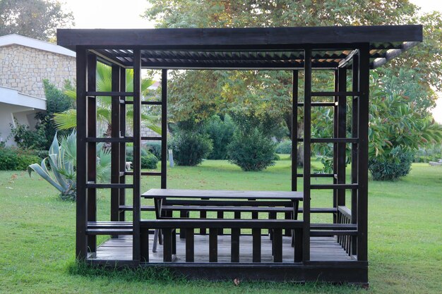 a gazebo with a bench on the grass and a bench in the middle