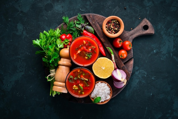 Gazpacho Soup in Glas. Tomato soup with onion, paprika and parsley. Italian cuisine. Top view. On a black background. Free space for text.