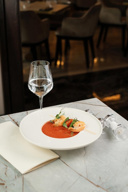 Gazpacho with shrimps Serving food in a restaurant with glass of water and menu