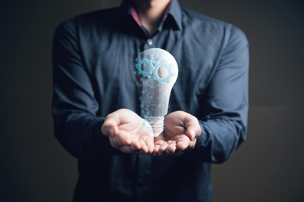 Gears in a light bulb from the network concept mechanism of ideas Man holding in his hand