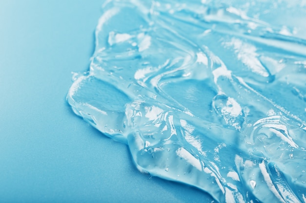 Gel with hyaluronic acid in the form of a smear of glossy texture on a blue surface