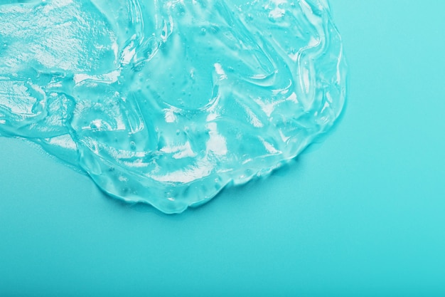 Gel with hyaluronic acid in the form of a smear of glossy texture on a cyan surface