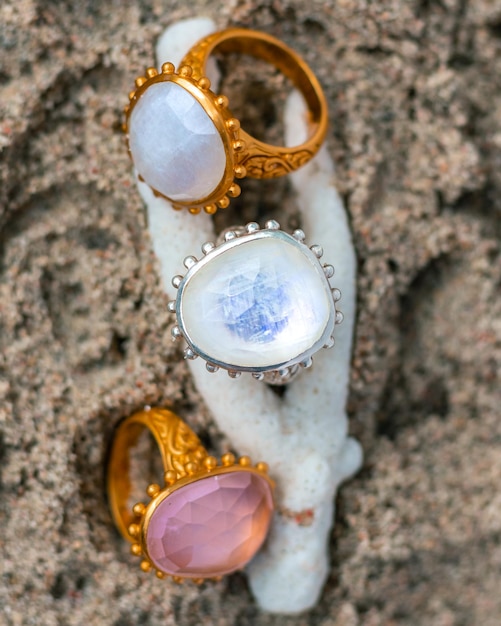 Photo gem stone rings on a coral on the beach jewelry product photos