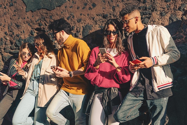 Photo gen z friends carefree talking and browsing social media contention the smartphones - young people sharing internet contents outdoors