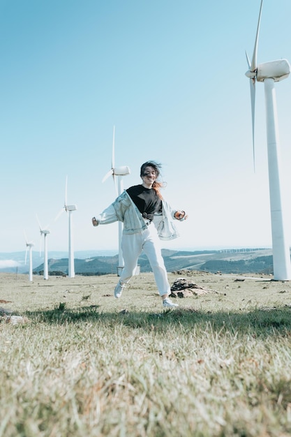 Gen Z girl running surrounded by eolic electric energy powered windmills new power resources conceptSave the plane clean world and new generations conceptBetter future carefree happy fun motion