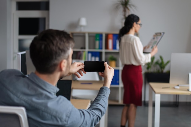 Gender discrimination and career perverted guy taking mobile photo of his female colleague without