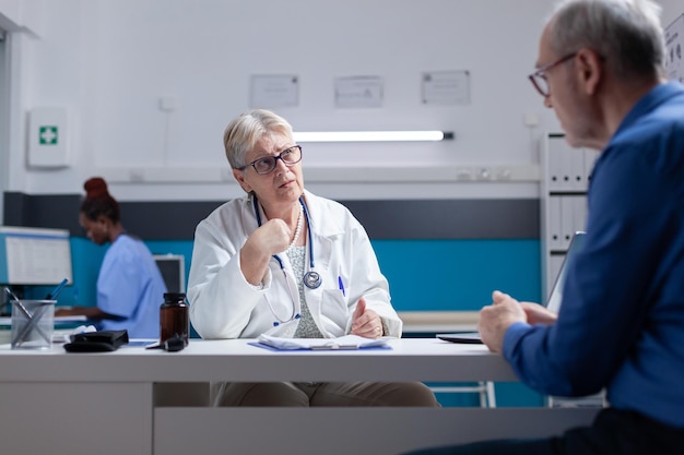 General practitioner having discussion with man at checkup visit in medical office. Physician doing healthcare consultation with senior patient, giving advice about disease diagnosis.