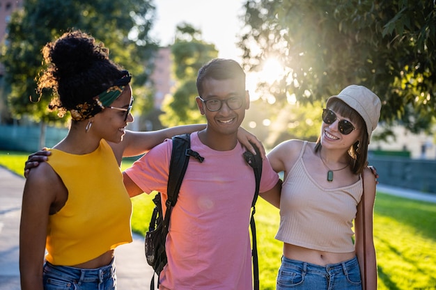 Generation Z friends walking on sunset in a park one boy and two girls having fun and spending time together on vacation