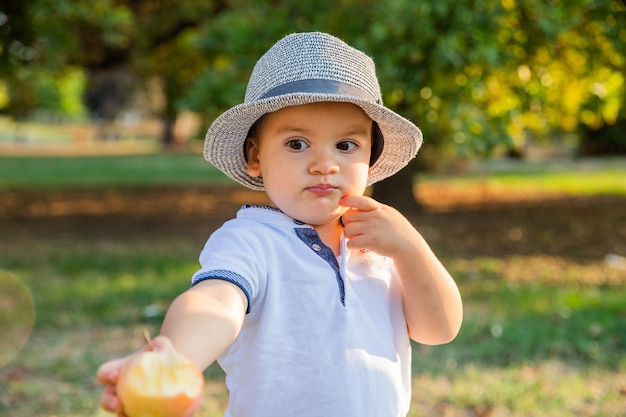 Generous child during picnic in the park offers his bitten apple with kindness