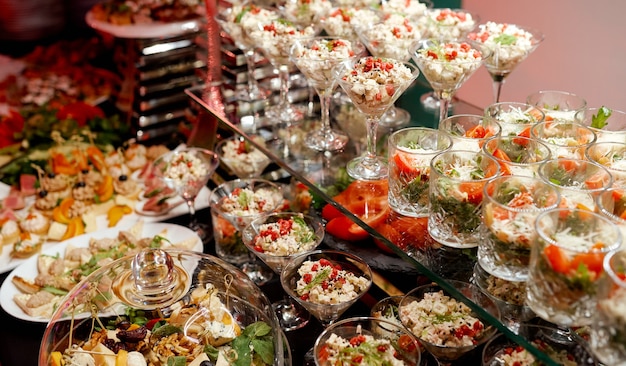 Generous table with salads and appetizers on glass shelves and in glassware . High quality photo