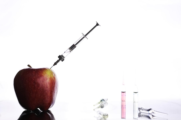 Genetically modified foods, apple pumped with chemicals from a syringe