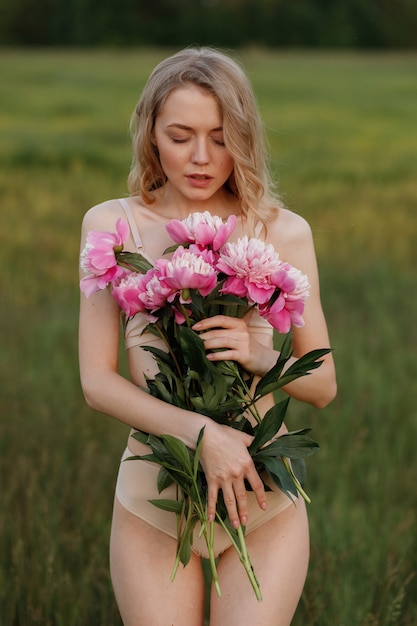 Gentle girl with pink flowers in her hands on a green background