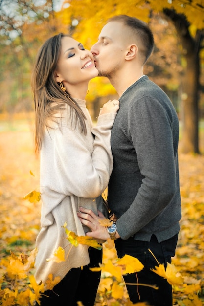 Gentle kiss on a date of a young couple in the autumn park