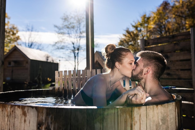 Photo gentle kiss of a young couple enjoying and relaxing in a private spa area an outdoor hot tub in a