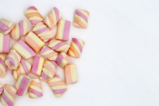 Gentle pink and yellow color marshmallows on white background with copy space. Sweet food. Pastel color.